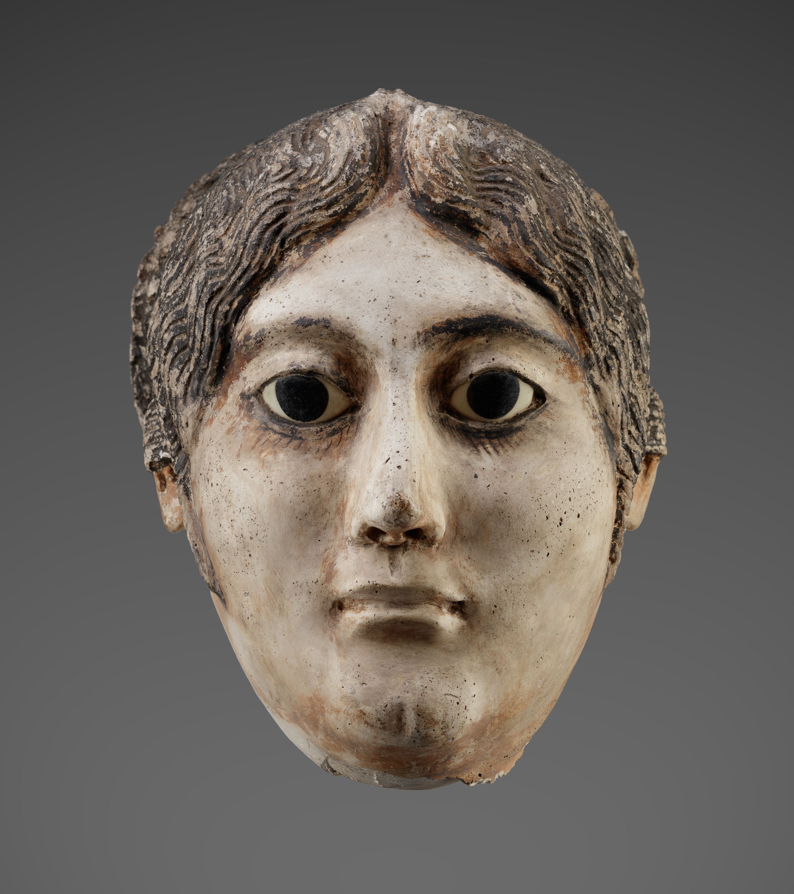 Mask of a woman with a large coil of plaited hair